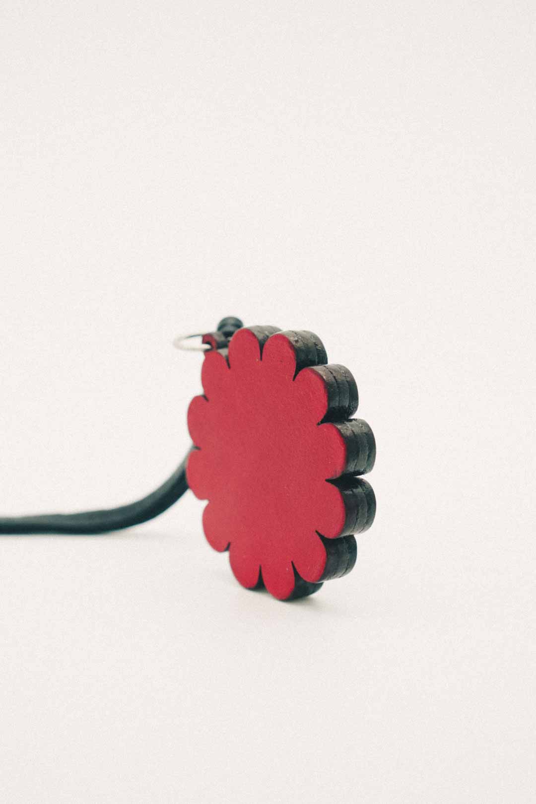 Backside of a red flower handmade leather bag charm on a light background