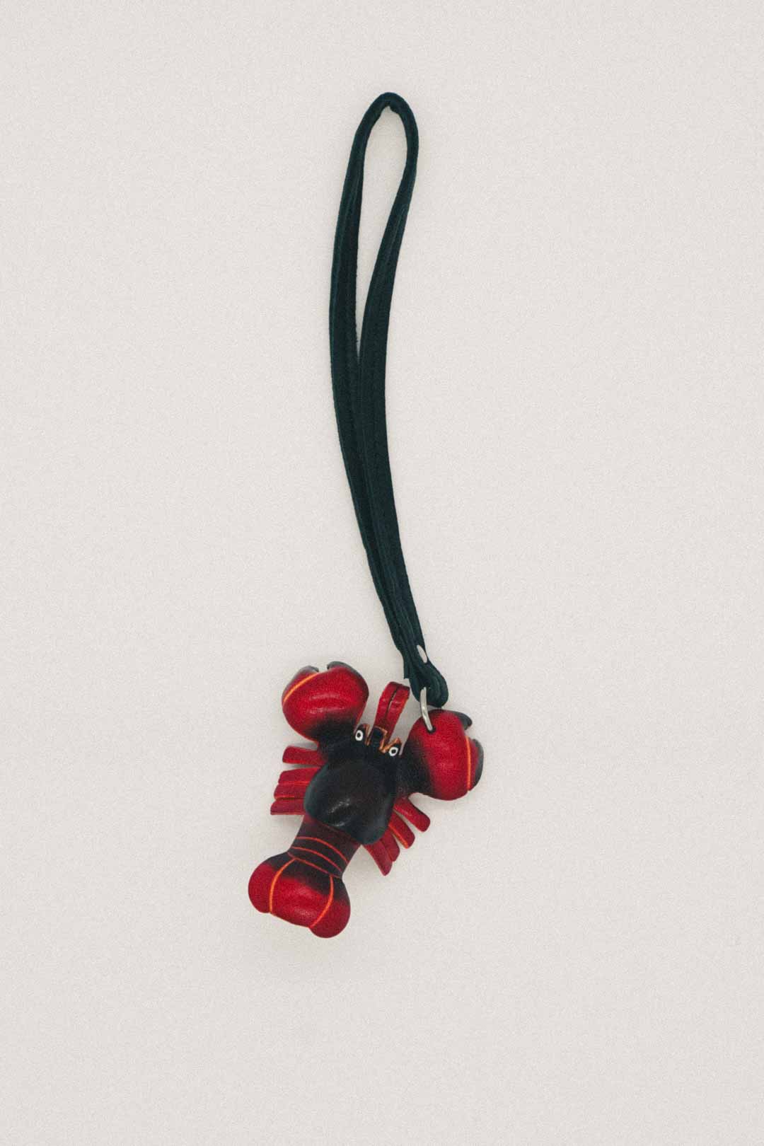 Red and black lobster-shaped keychain with a strap on a light gray background