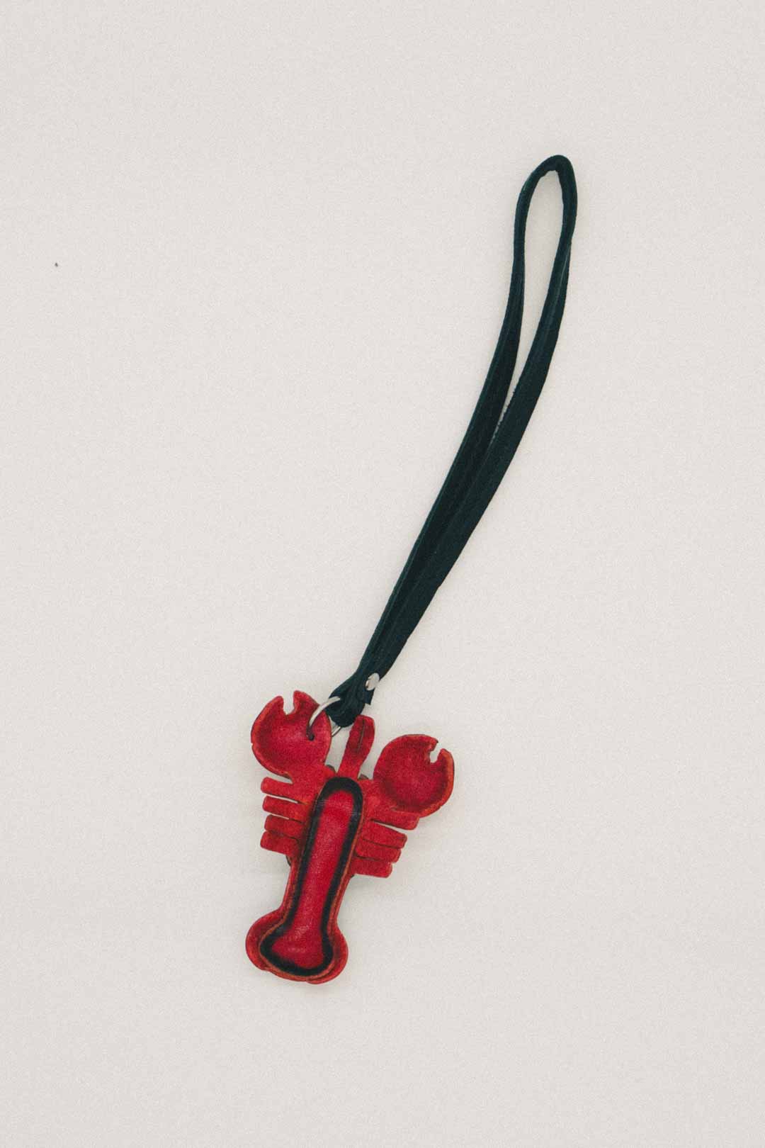 Under side of a red lobster shaped keychain with a black strap on a white background