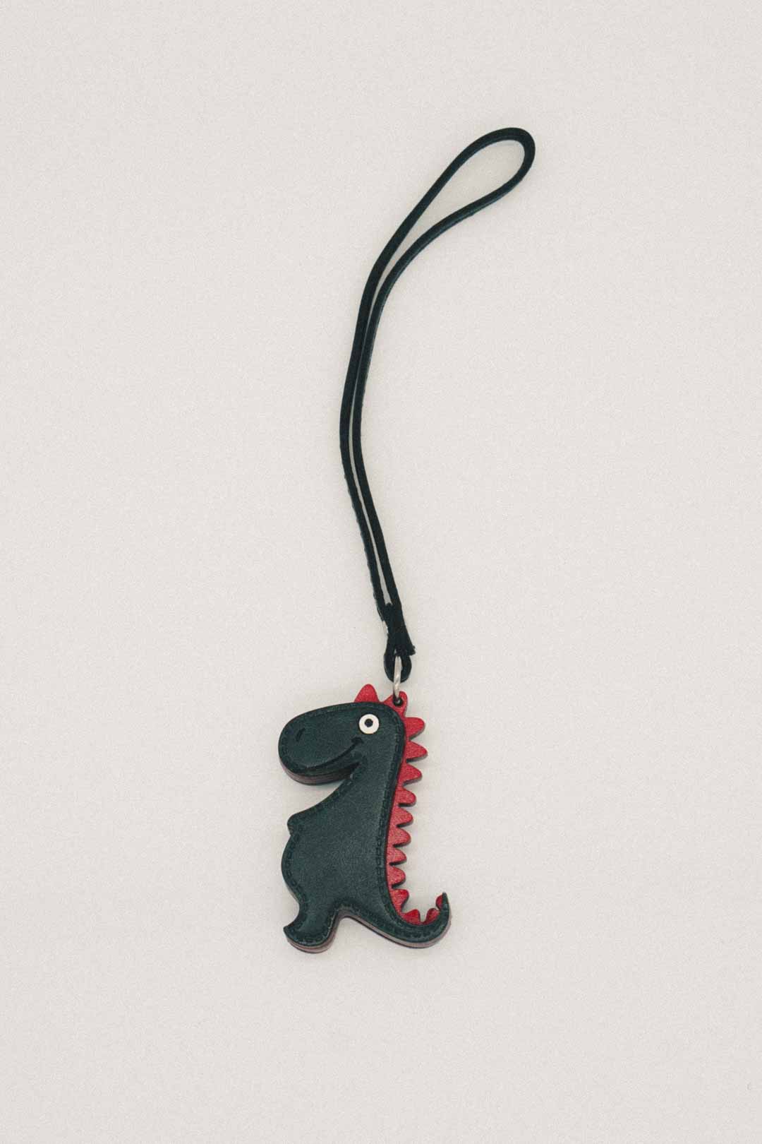 Dinosaur-shaped handmade leather bag charm on a white background