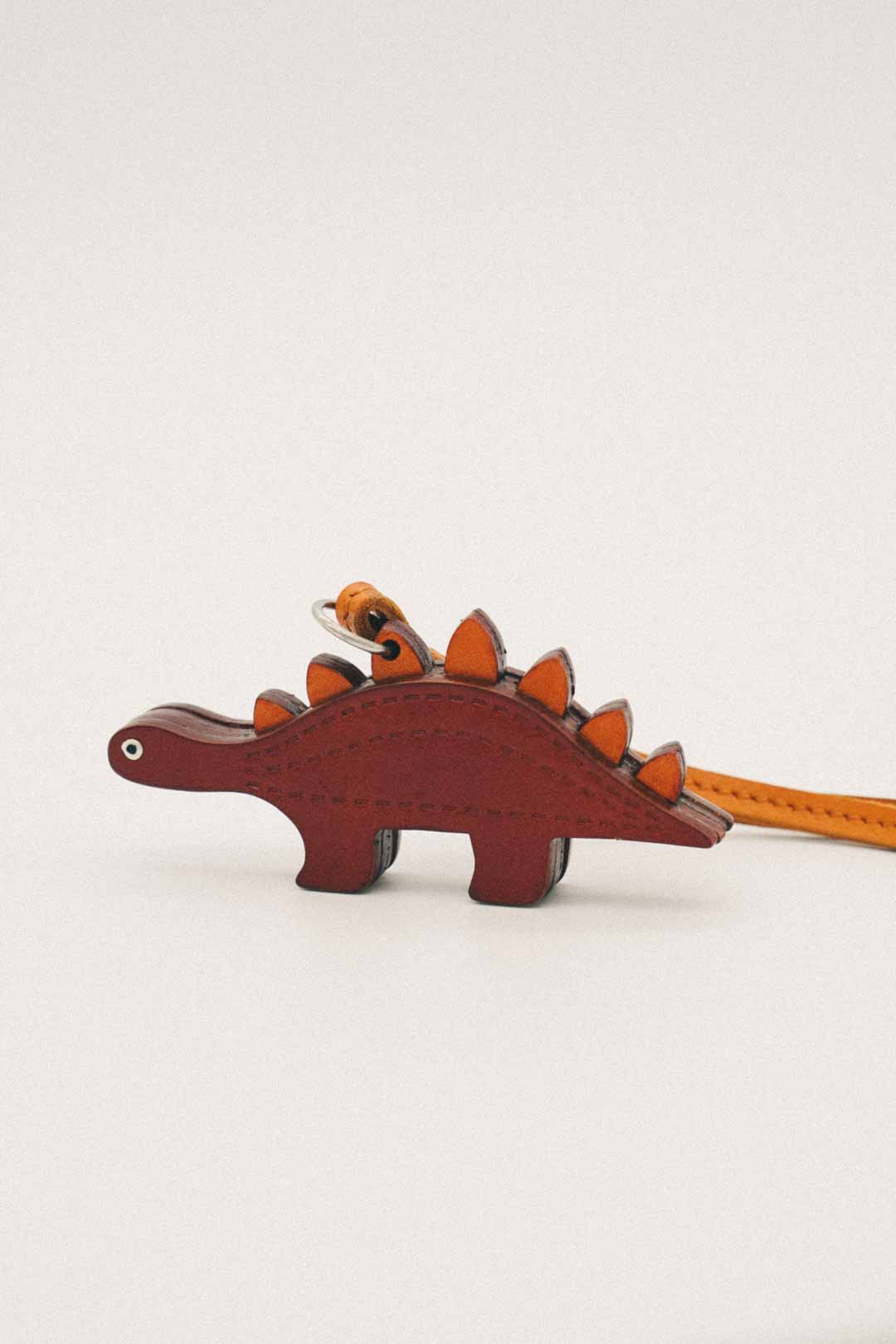 Dinosaur-shaped handmade leather bag charm on a white background