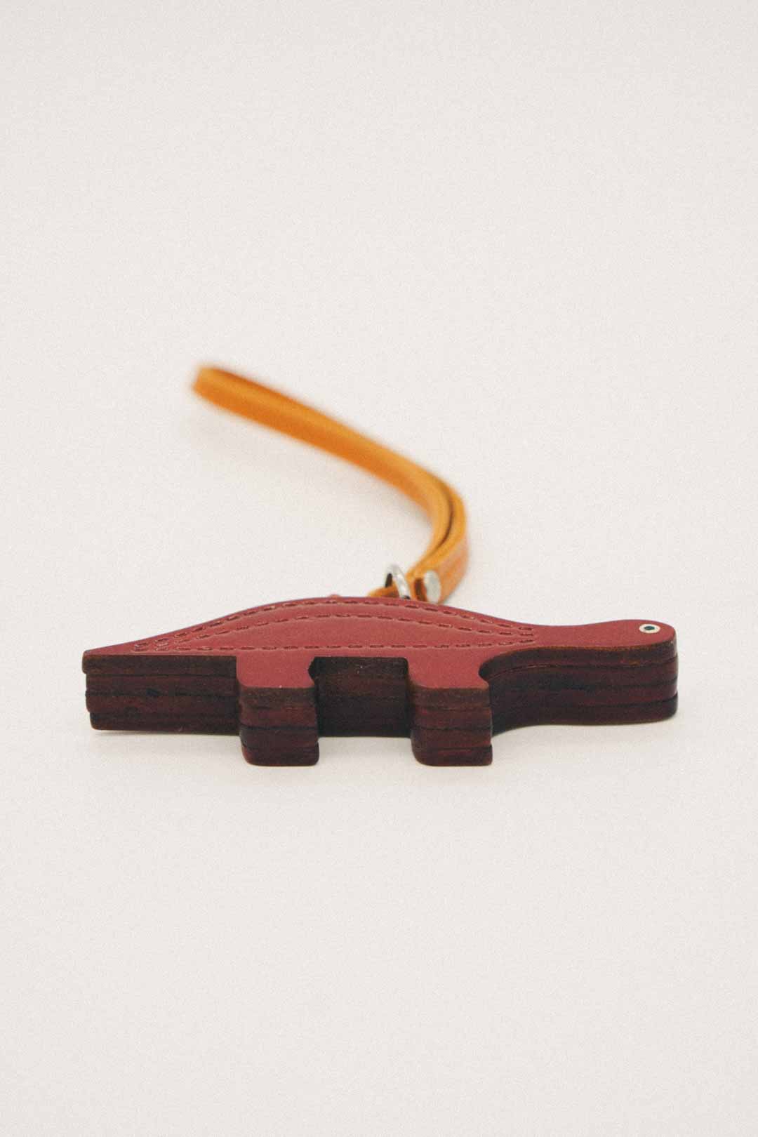 Dinosaur-shaped keychain with a strap on a white background