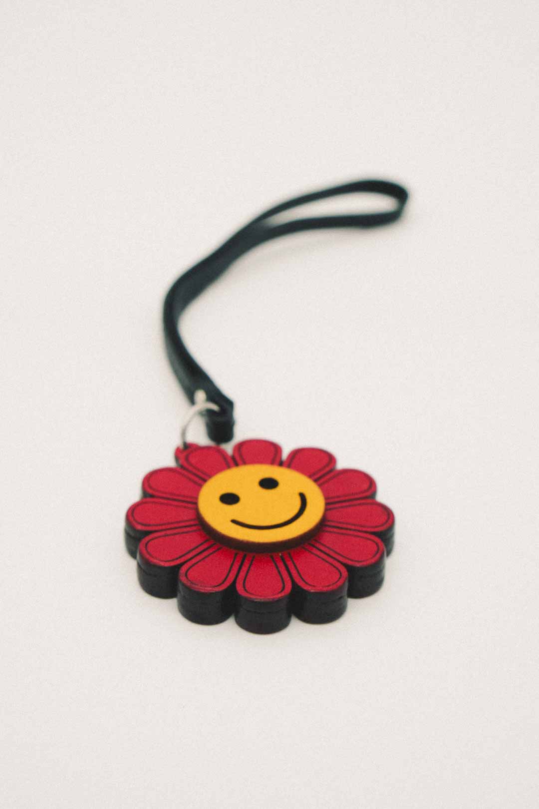 Red and yellow keychain with a smiley face flower design on a white background