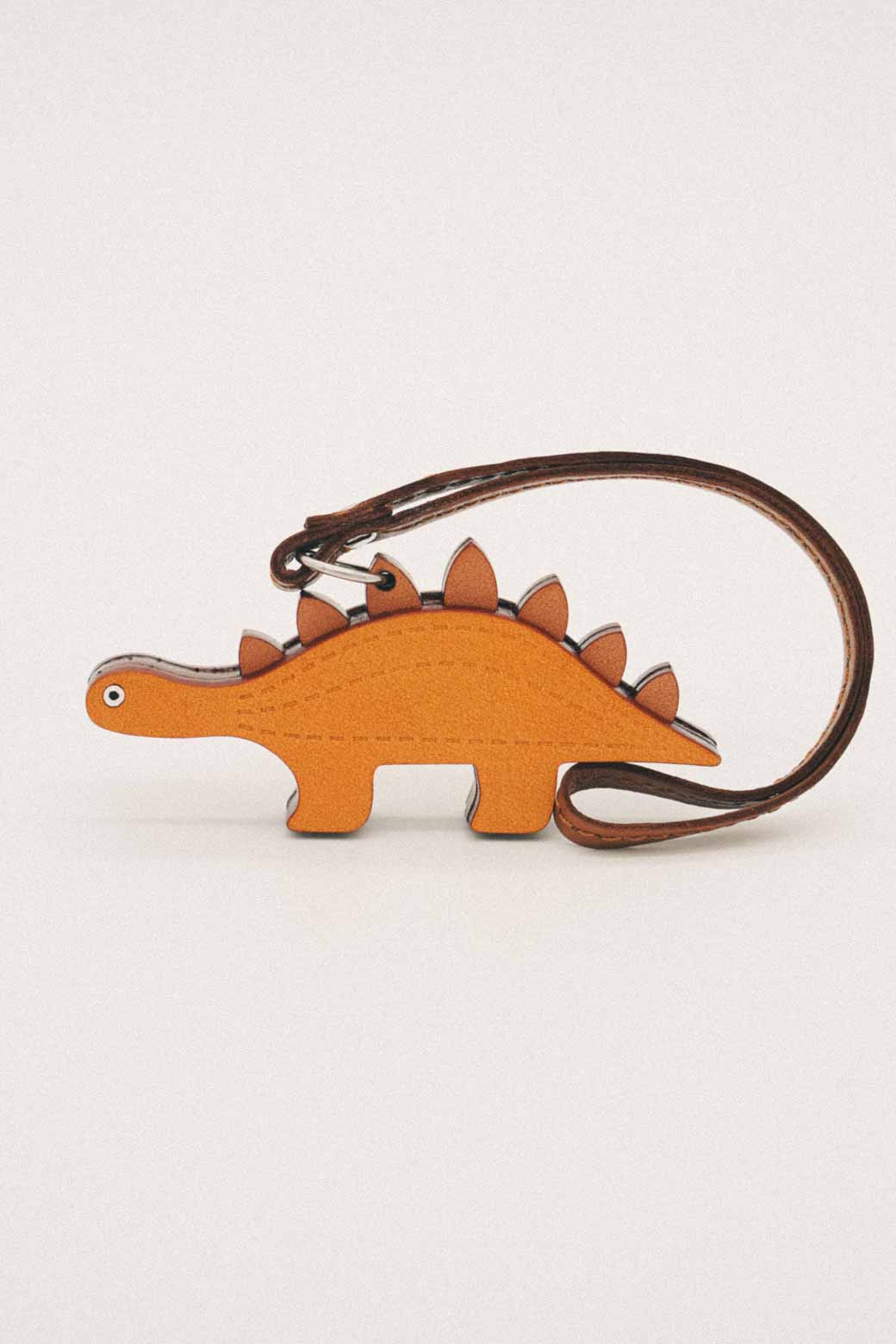 Orange dinosaur-shaped handmade leather bag charm on a white background