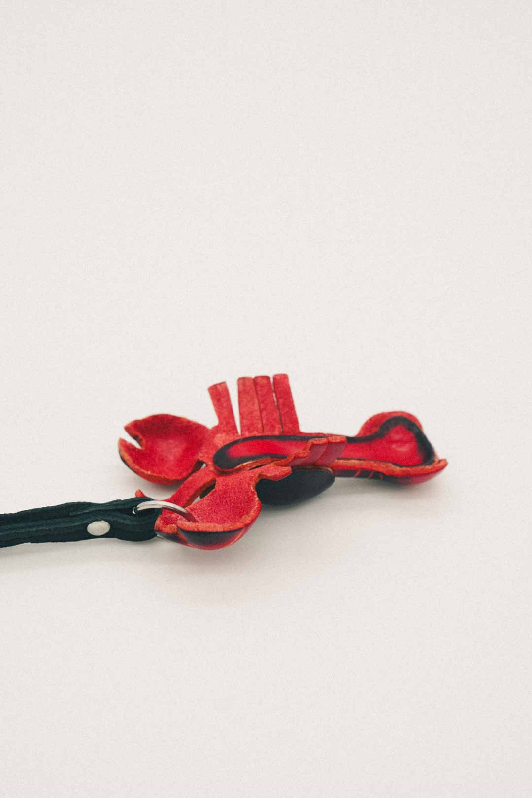 Side view of the underside of a handmade leather bag charm shaped as a lobster