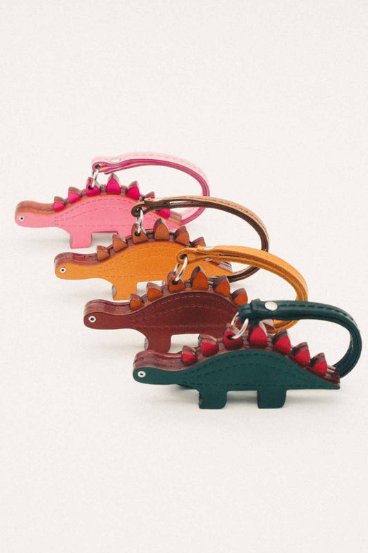 Four dinosaur-shaped handmade leather bag charms in different colors on a white background