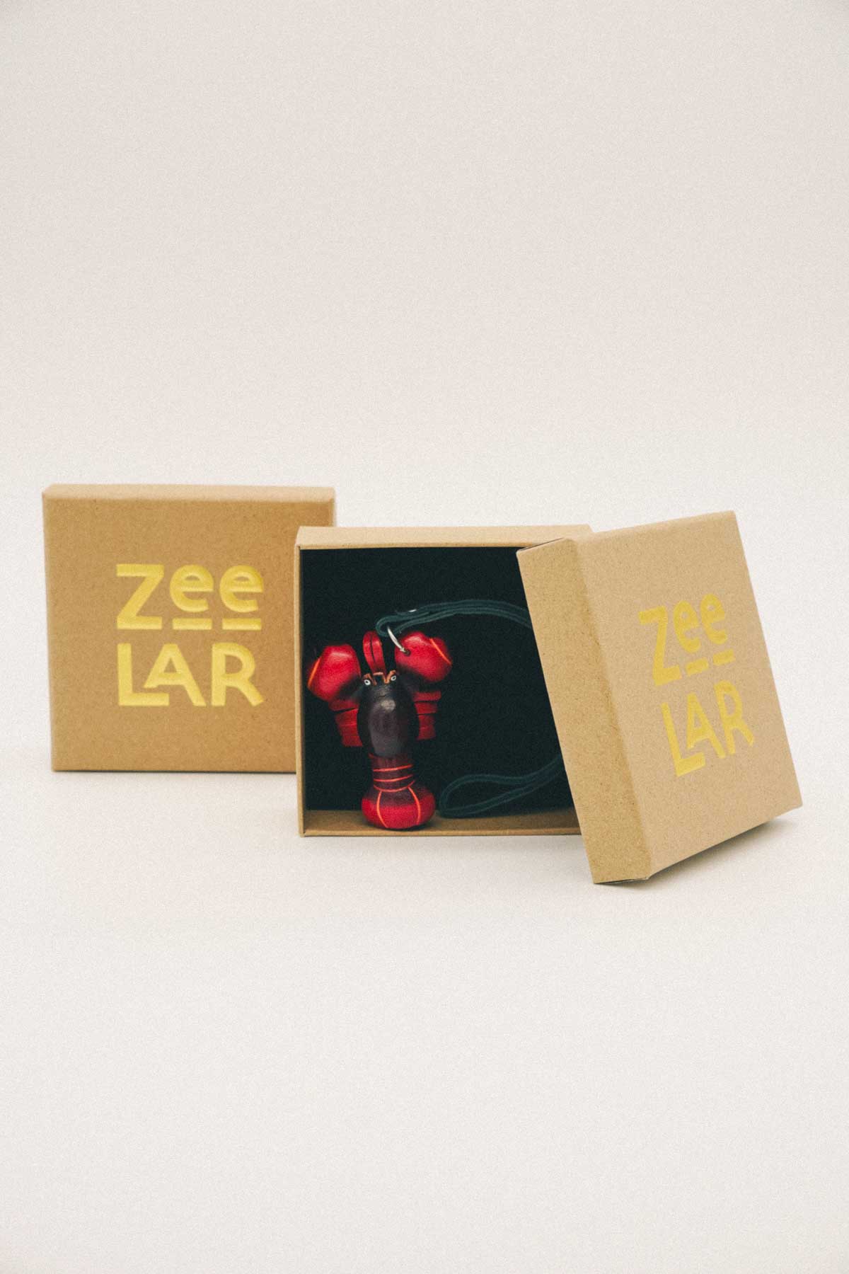 Red lobster handmade leather bag charm inside a cardboard box featuring 'Zeelar' branding