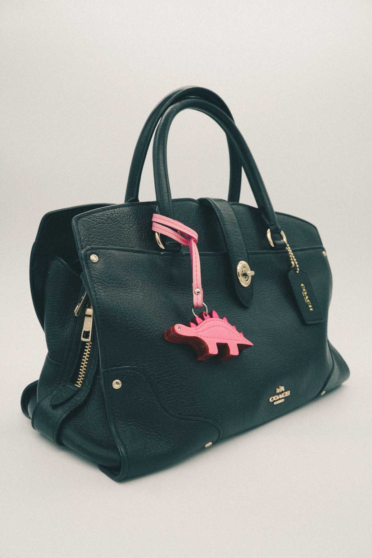 Black bag with pink dinosaur handmade leather bag charm on white background